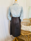Jupe en cuir véritable vintage 80's marron glacé T.38 seconde main – vue de dos portée avec chemise en jean bleu ciel styling inspiration