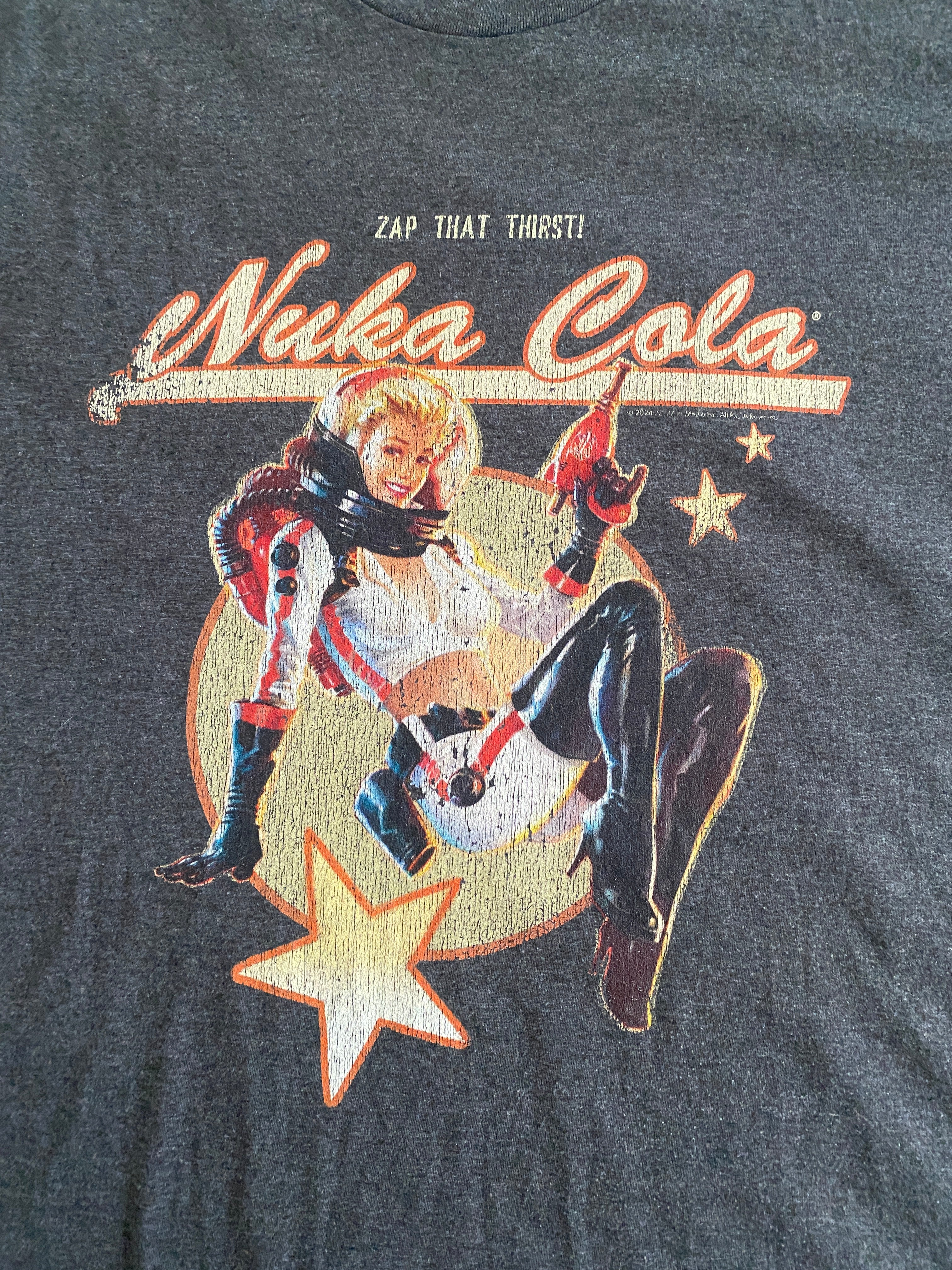 T-shirt Fallout Nuka-Cola – détail flocage face, inscription Zap That Thirst et Nuka Cola, pin-up en combinaison rouge et noire sur fond doré