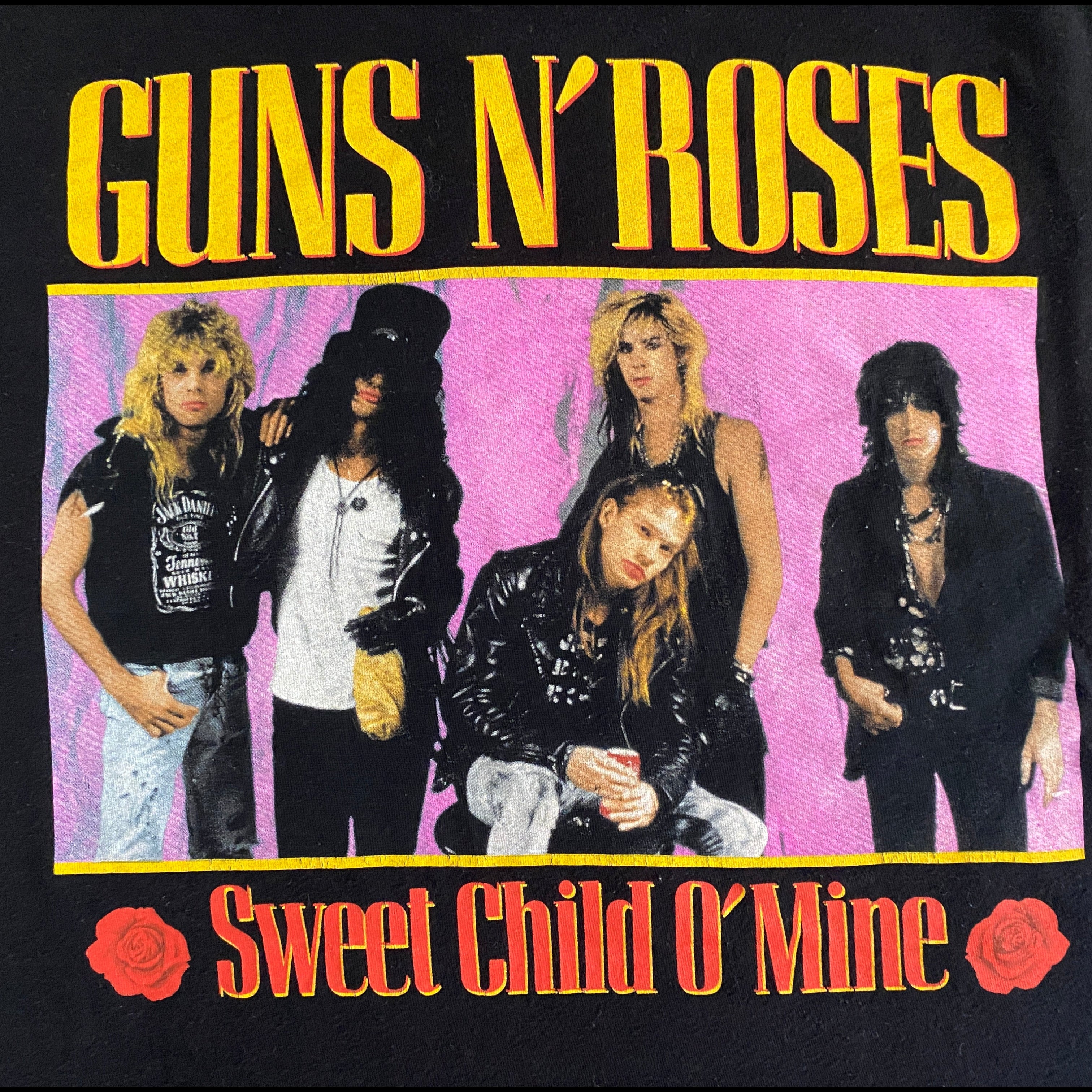 T-shirt Guns N' Roses Sweet Child O' Mine – détail flocage dos, photo de groupe sur fond rose flashy avec roses rouges et lettres jaunes et rouges