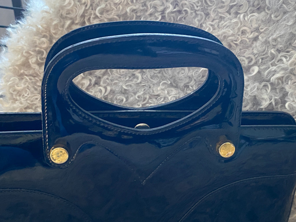 Sac vintage vinyle noir – détail poignée sculptée galbe en V et rivets dorés – années 60