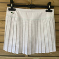 Skort tennis Lacoste Sport, vue de face sur cintre, blanc et jupe plissée à carreaux