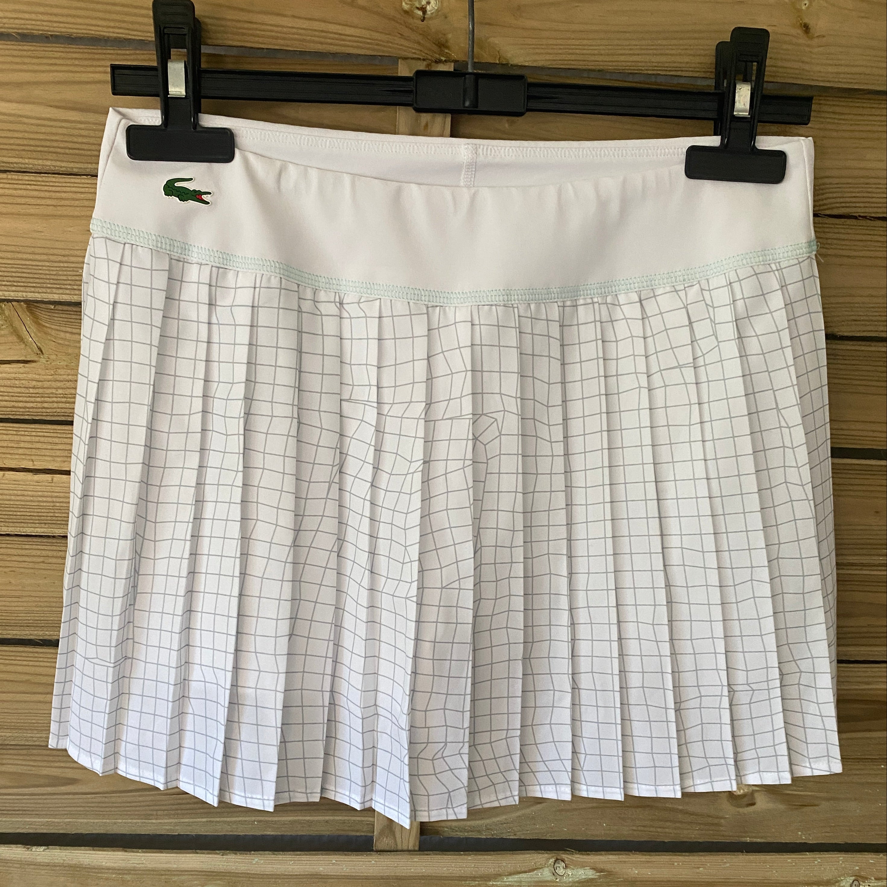 Skort tennis Lacoste Sport, vue de face sur cintre, blanc et jupe plissée à carreaux