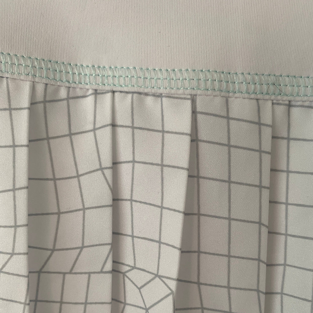 Détail motif carreaux du tissu et liseré vert d'eau Lacoste Sport