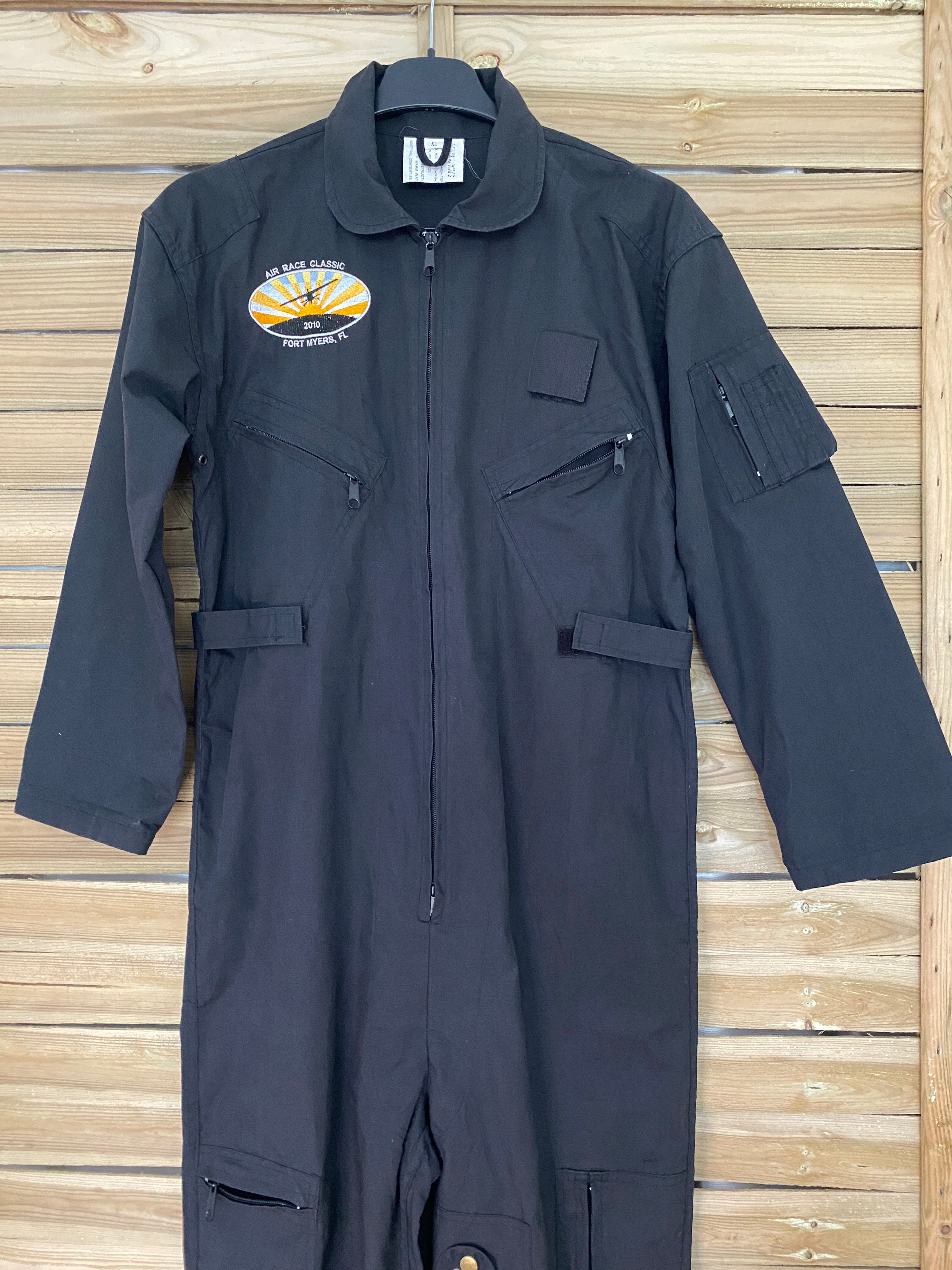 Combinaison flight suit noire – focus buste : poches poitrine zippées, patch brodé et double zip central