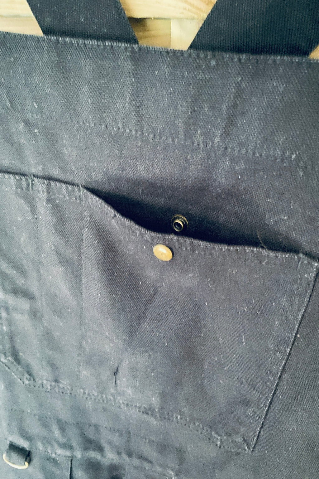 Vue de face de la salopette SÜK, détail tablier avec poche plaquée et rivets en laiton dorés