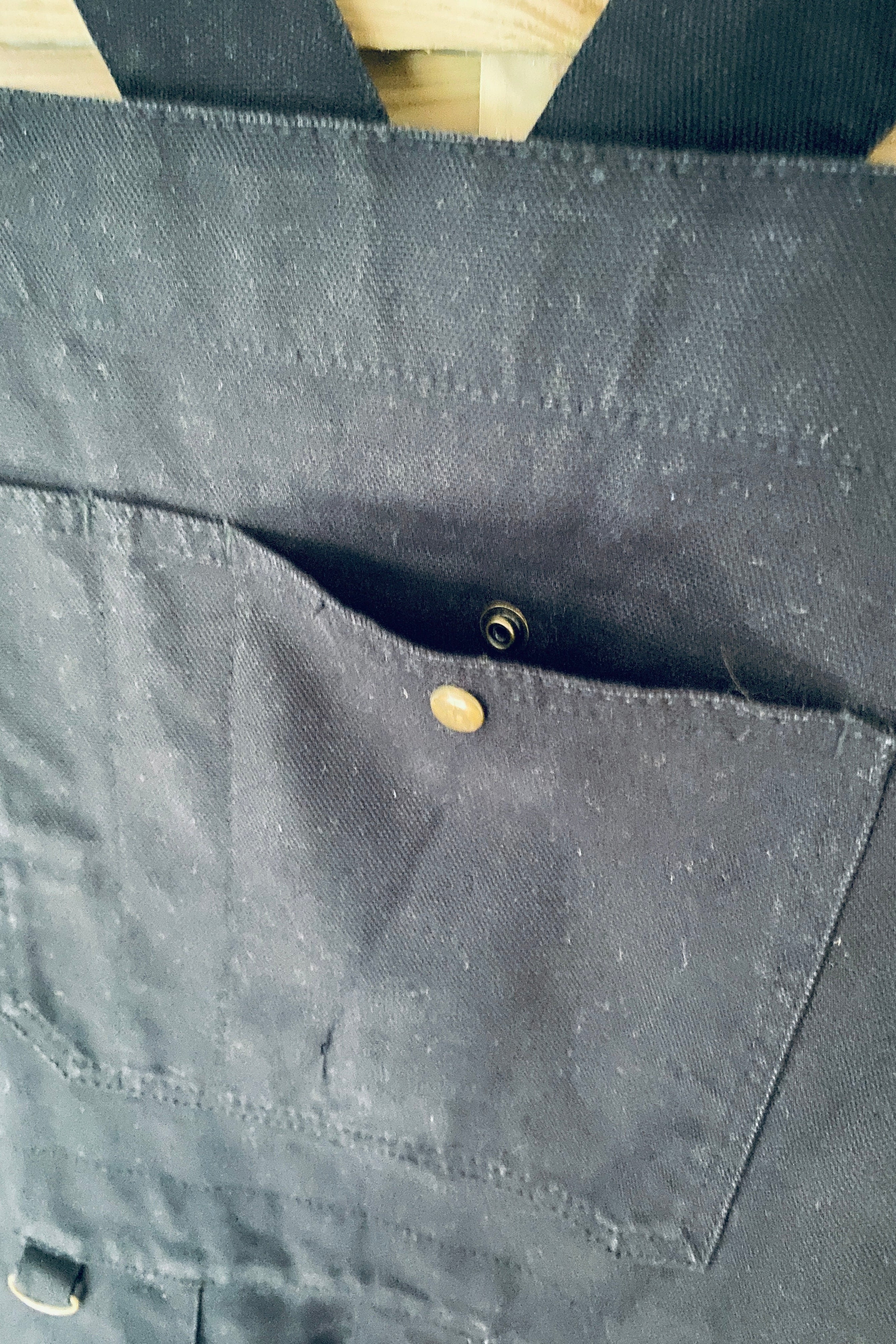 Vue de face de la salopette SÜK, détail tablier avec poche plaquée et rivets en laiton dorés