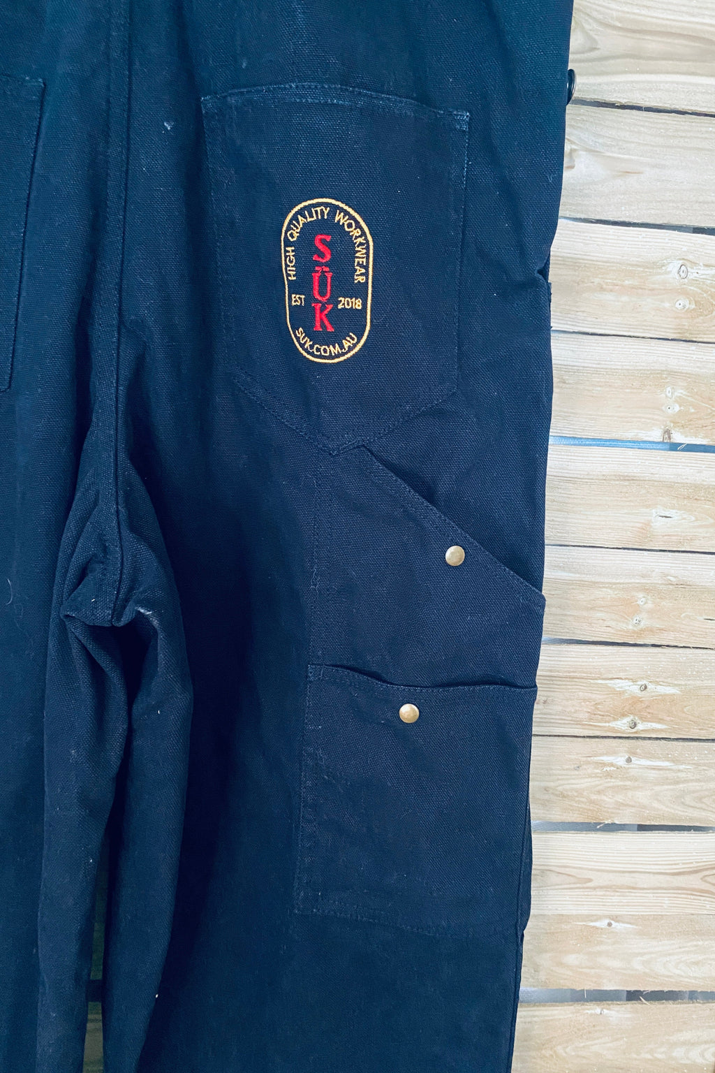 Vue de dos de la salopette SÜK, détail poche arrière et patch brodé logo SÜK High Quality Workwear