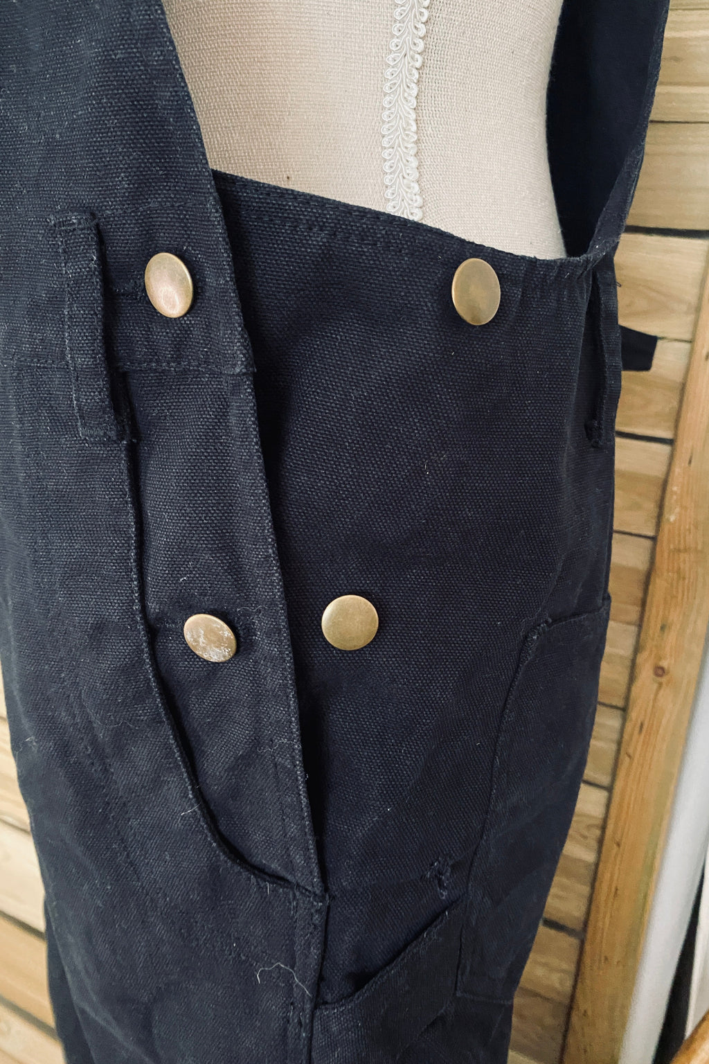 Vue de côté de la salopette SÜK, détail du système d'ajustement de taille par boutons-pression sur les flancs