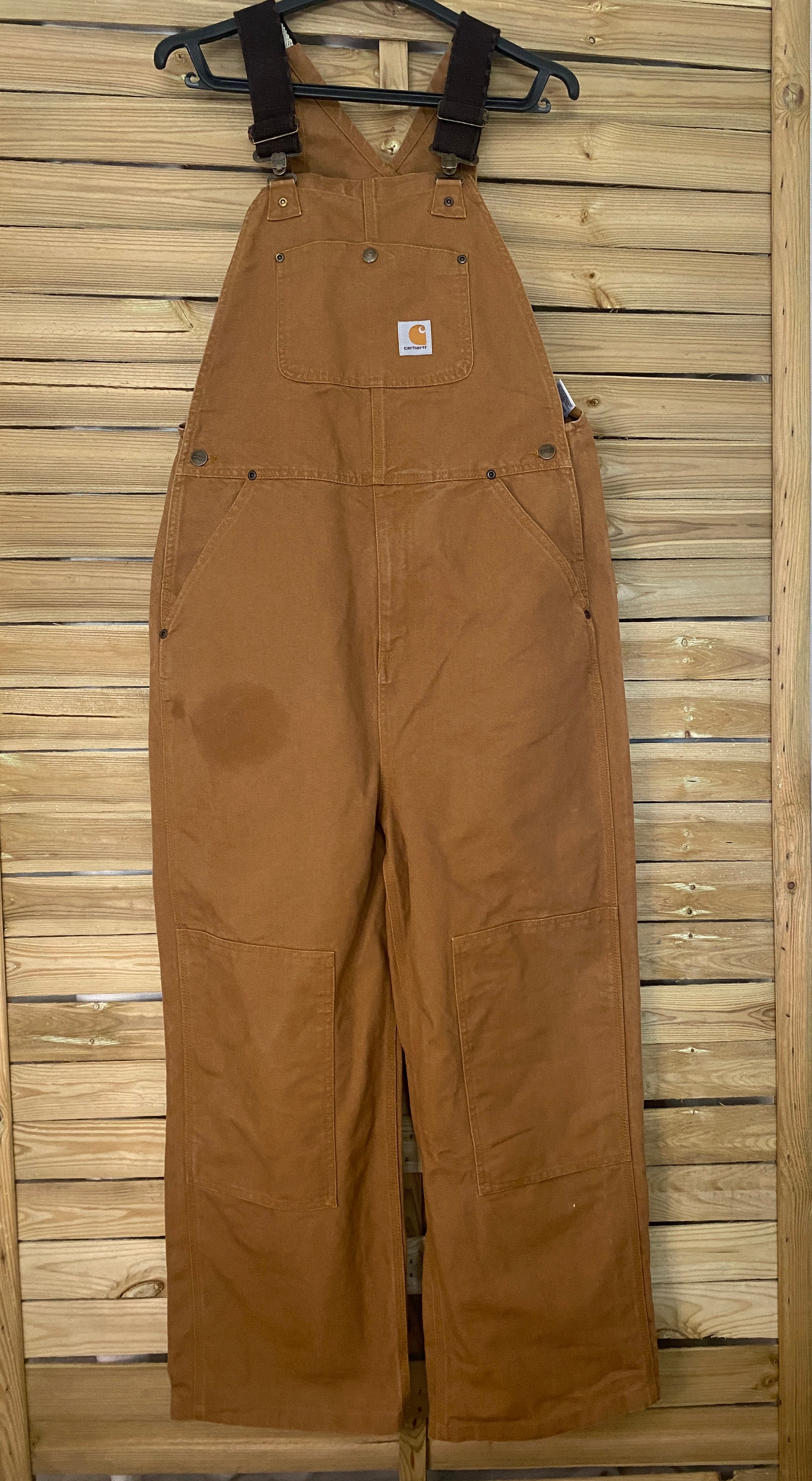 Salopette workwear Carhartt Duck Brown vue de face sur cintre, denim épais 100% coton coloris caramel iconique