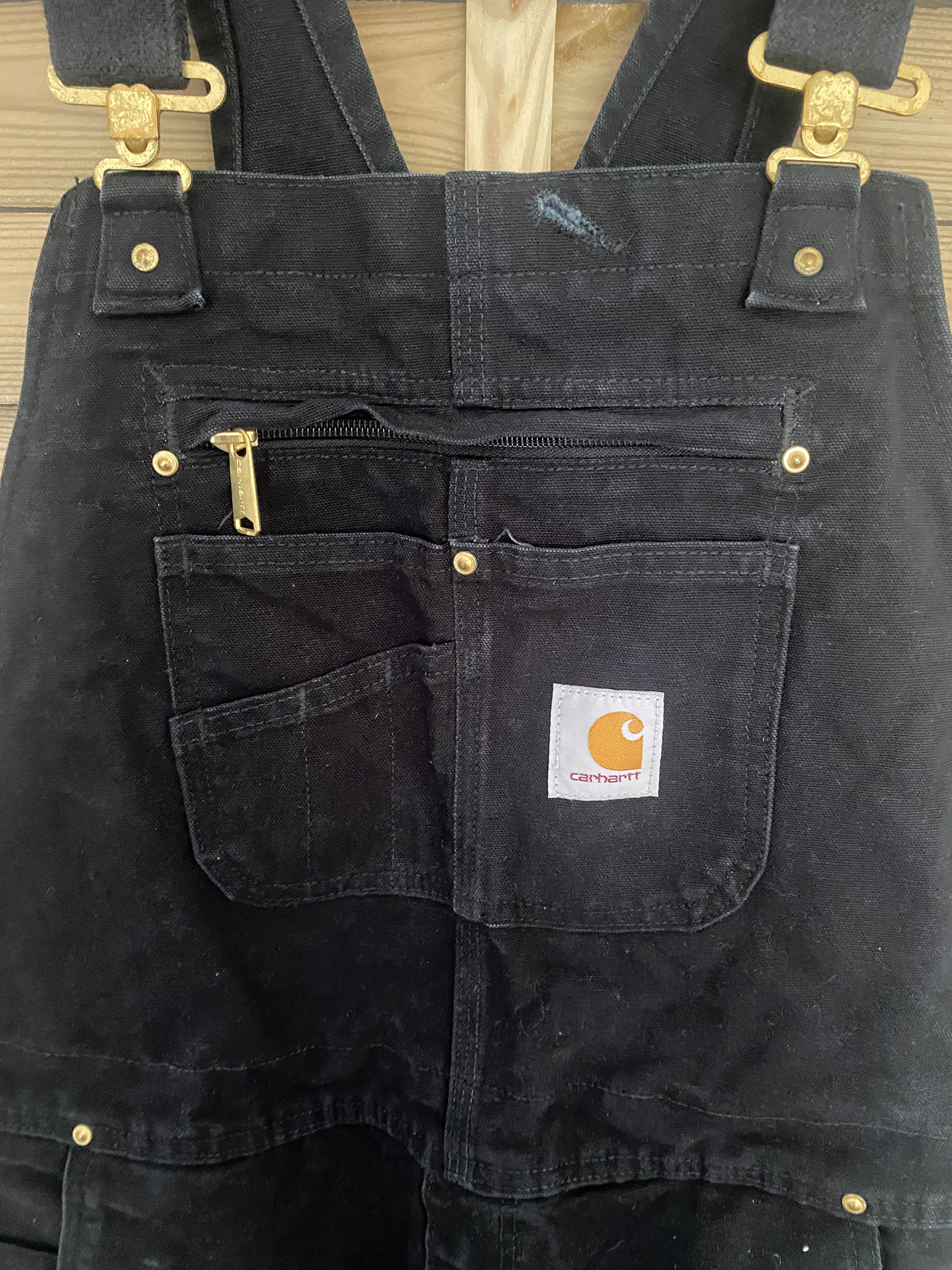 Détail poche zippée tablier et boutonnière – Salopette Carhartt Zip-to-Thigh noire
