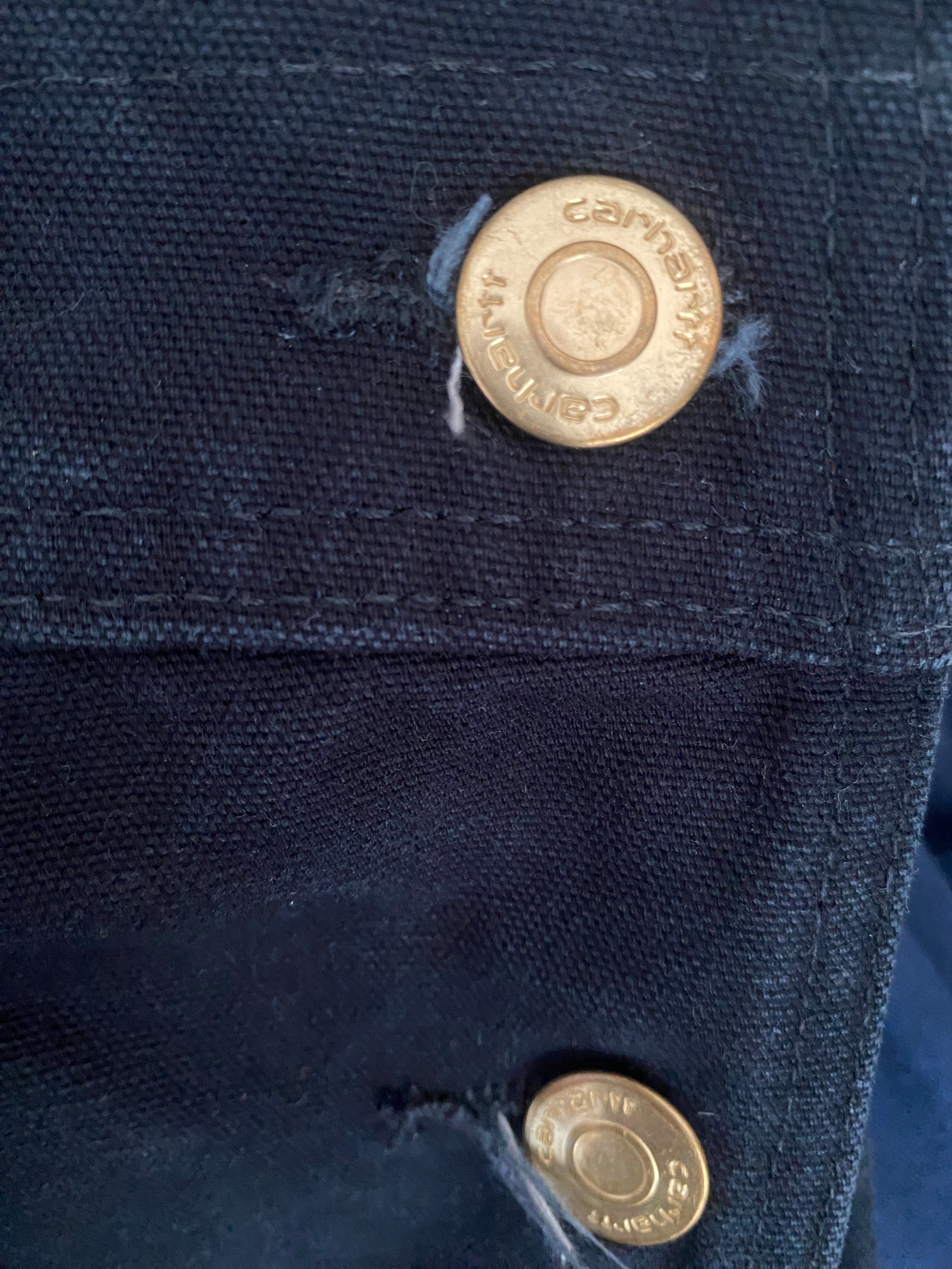 Détail boutons gravés Carhartt – hardware doré patiné salopette workwear noire