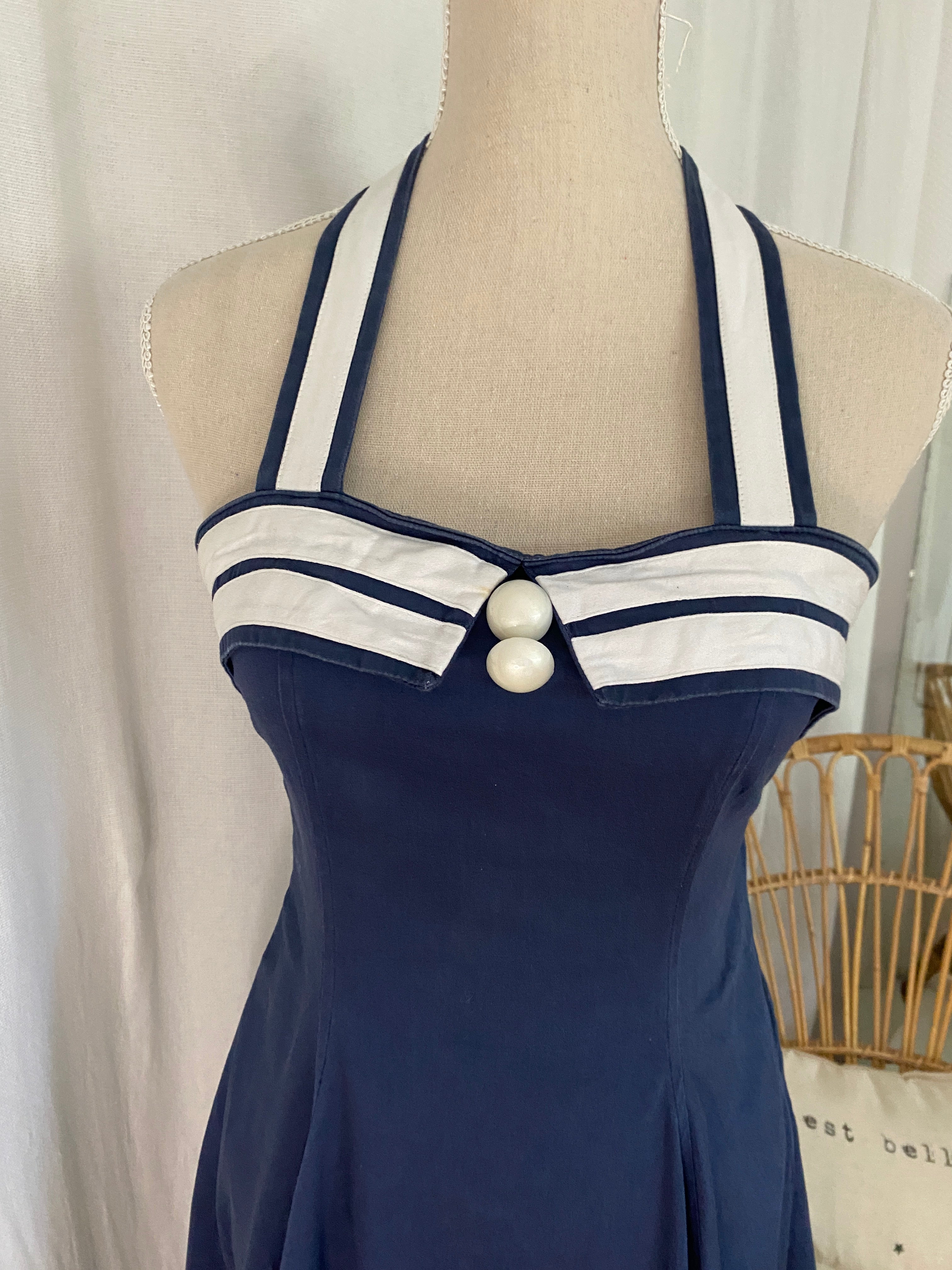 Détail bustier sweetheart de la robe Collectif, deux boutons ronds au décolleté, liseré blanc et bretelles halter rayées marine et blanc