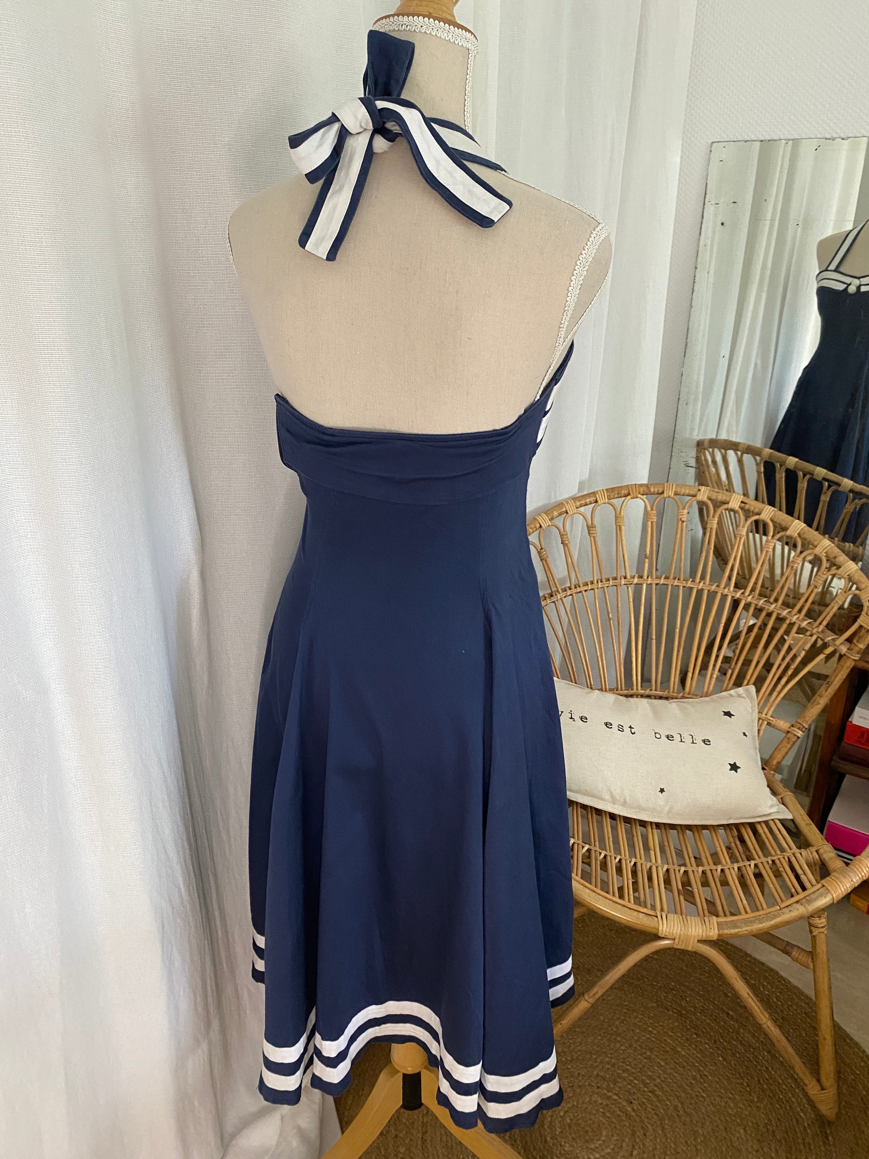 Dos nu de la robe pin up sailor Collectif, nœud rayé marine et blanc noué dans le dos, jupe évasée à godets avec doubles bandes blanches en bas